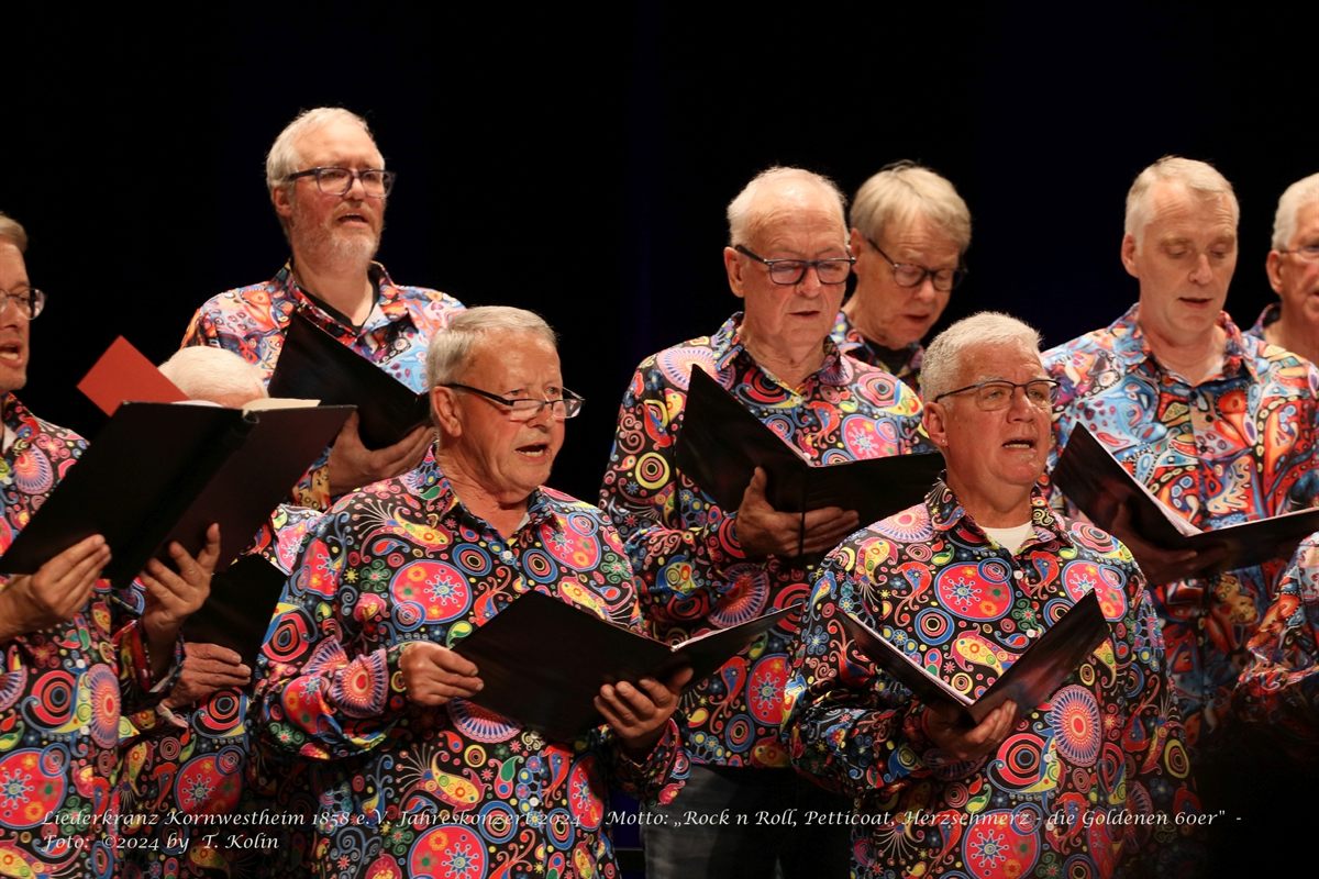 Nahaufnahme singender Chormitglieder in bunten Hemden beim Jahreskonzert.